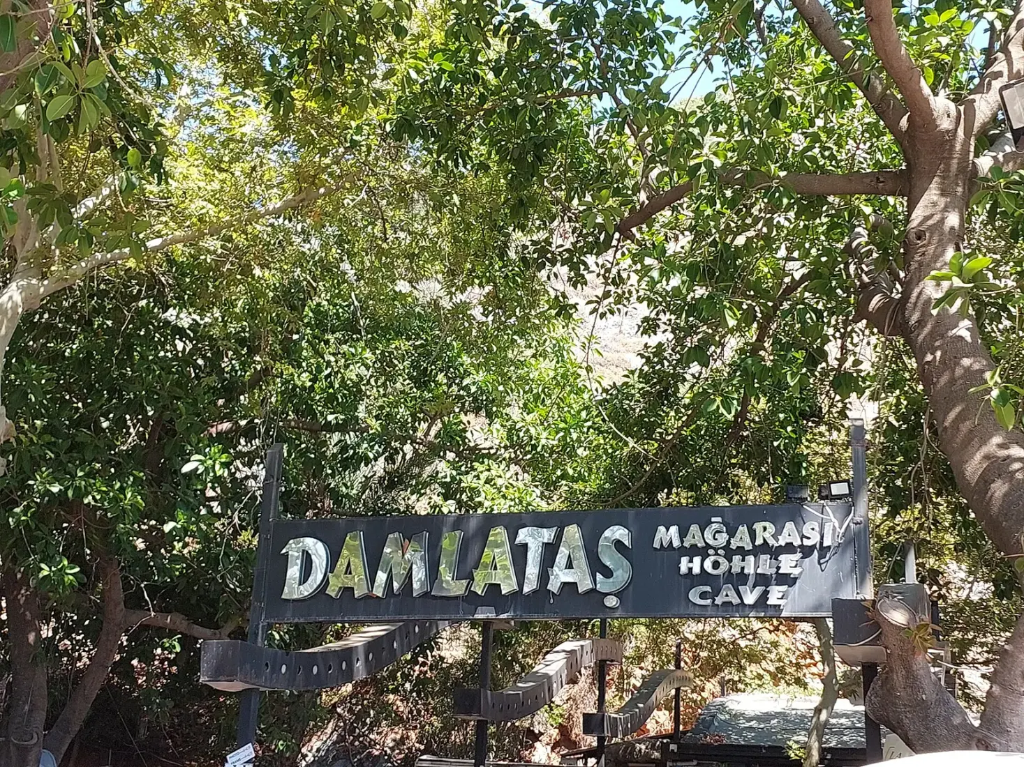 De ingang van de Damlataş grot onder de bomen vlak bij het strand van Alanya