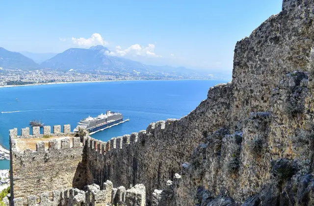De gekanteelde oostmuren van het kasteel van Alanya boven de haven en de baai