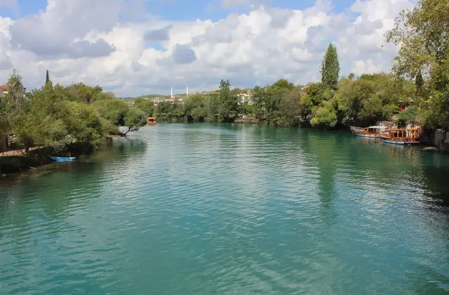 De groenblauwe Manavgat rivier tussen begroeide oevers in de stad Manavgat
