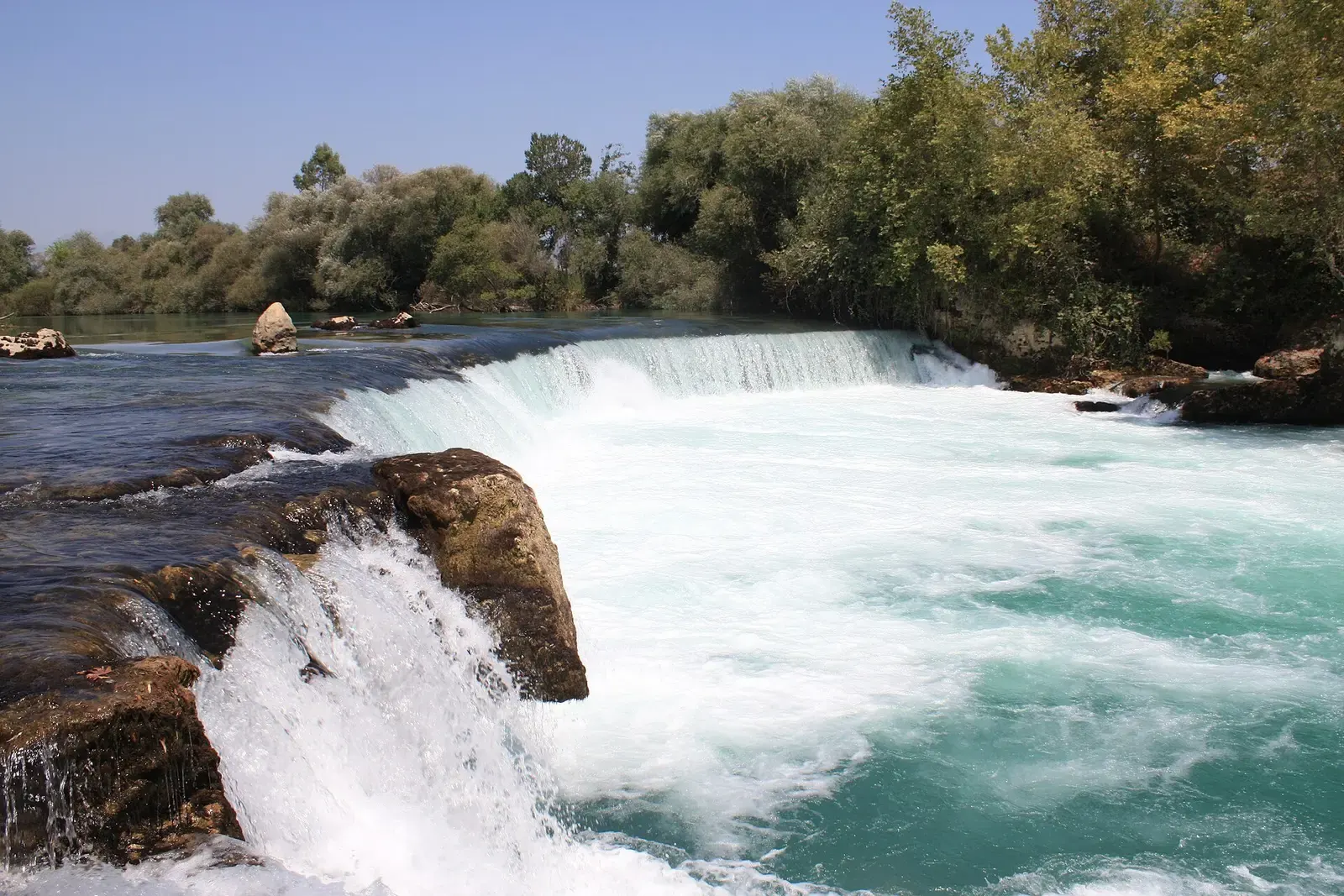 Wit schuimend water dat over de kalksteenrand van de Manavgat waterval stort