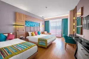 Ruime familiekamer in Long Beach Alanya met bed, zithoek en kleurrijke accenten.