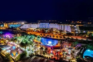 Long Beach Alanya in de avond met verlichte zwembaden en gebouwen.