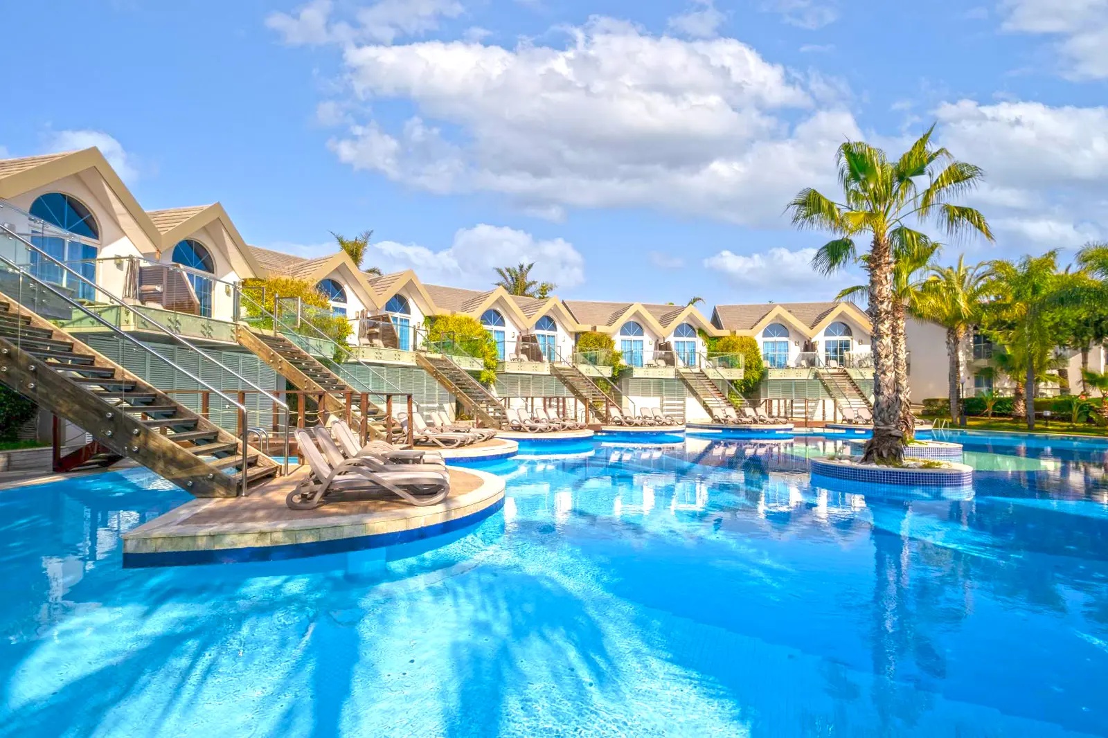 Zwembad met palmbomen en villa’s bij Long Beach Alanya.